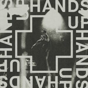Cover artwork for Jelly Roll's single “Hands Up,” featuring a black-and-white live performance image framed by a cross with the title “Hands Up” surrounding it. Title: Jelly Roll – Hands Up Single Artwork Caption: Official artwork for Jelly Roll's single “Hands Up.” Description: Official single artwork for Jelly Roll's “Hands Up.” The black-and-white design features a live performance image of Jelly Roll inside a cross-shaped frame, with the words “Hands Up” displayed prominently around the artwork.